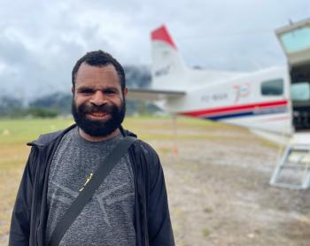 Justin Petrus, a teacher at Eliptamin after arrival in Telefomin posing in front of the MAF plane