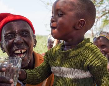 A happy child savors a refreshing glass of clean water.